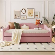 a pink daybed in a white room with pictures on the wall