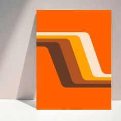 an orange card with brown and white lines on the front, against a gray wall