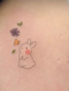 the back of a woman's shoulder with a small rabbit and flowers on it