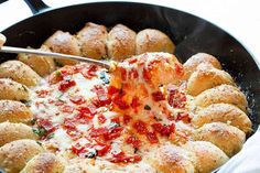 a pan filled with bread and cheese covered in marinara sauce being spooned into it