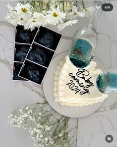 a birthday cake with blue icing and flowers on the table next to it is an image of a baby's birth