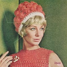 a woman wearing a red knitted hat with flowers on it's head and an arrow in her hand