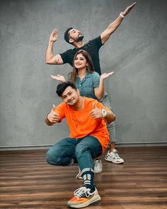 three people sitting on the floor with their arms in the air and one person standing behind them