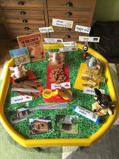 a yellow tray filled with lots of toys and books on top of green carpeted floor