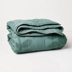 two folded towels sitting on top of each other in front of a white wall and floor