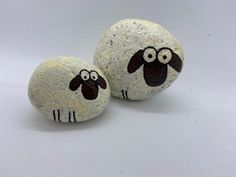 two painted rocks with sheep faces on them