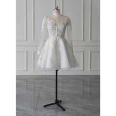 a wedding dress on a mannequin stand in front of a white wall and floor