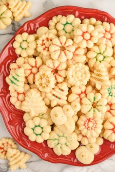 a red plate filled with white and green christmas sprinkles on top of a marble counter