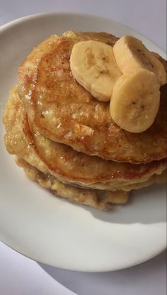 pancakes with bananas and syrup on a white plate