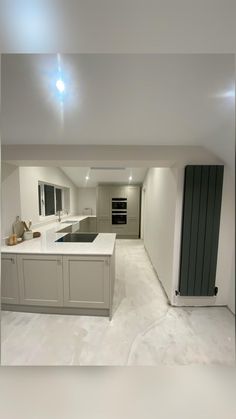 an empty kitchen with white counter tops and grey cupboards on either side of the island