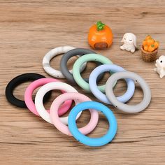 several different colored rubber rings on a wooden table with pumpkins and ghost figurines