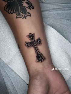 a person with a cross tattoo on their arm