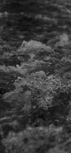 black and white photograph of water with small waves coming up from the rocks in the foreground