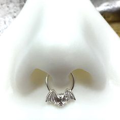 "Bat Septum Ring, Septum Hoop, Bat Nose Ring, Sterling Silver Nose Ring, Tiny Bat Septum Piercing, Septum Hoop, Bat Jewelry, Goth, Punk, Edgy WHAT IT IS AND WHY YOU WANT IT: The little bat on this septum ring is adorable AND a little spooky! The perfect combo! It is hand molded using fine silver in a mold I personally made just for this process. Then it is soldered to a solid sterling silver hoop. Choose the gauge and diameter you prefer. Solid gold option will be a 22k solid gold bat on a solid Bat Septum Piercing, Bat Nose Ring, Bat Nose, Cute Septum Rings, Sterling Silver Nose Rings, Septum Piercing Jewelry, Septum Hoop, Types Of Ear Piercings, Bat Jewelry