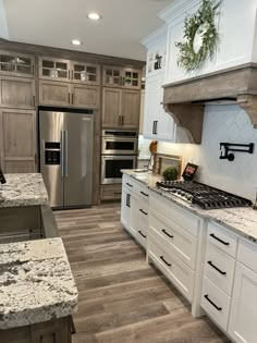 a kitchen with white cabinets and granite counter tops, stainless steel appliances and wooden flooring