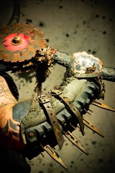 a person with tattoos holding something in their hand and wearing gloves that have spikes attached to them