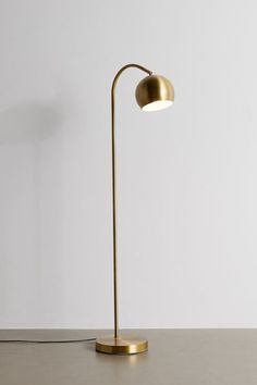 a gold floor lamp with a white wall in the background