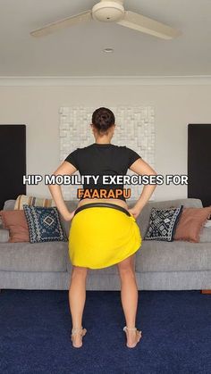 a woman standing in front of a couch with her back turned to the camera, wearing a black shirt and yellow skirt