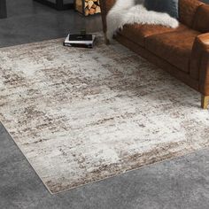 a brown couch sitting on top of a wooden floor next to a white and gray rug