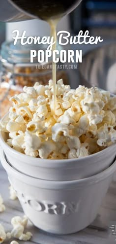 popcorn being poured into a white bowl on top of a wooden table with other food items