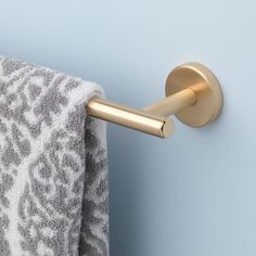 a towel hanging on the side of a blue wall with a gold metal hook in front of it