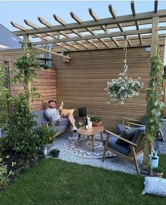 a man sitting in a chair on top of a grass covered patio next to a wooden fence