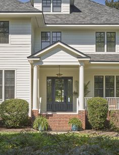 a white house with black shutters on the front door and windows in the side