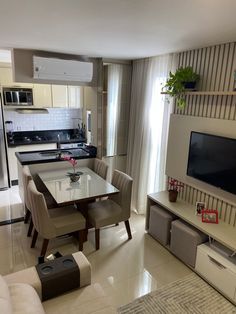 a living room and dining area with a television on the wall in front of it