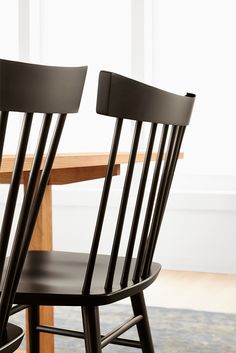 two black chairs sitting next to each other on top of a wooden dining room table