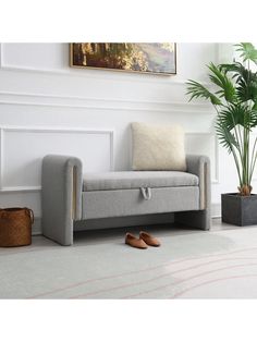 a grey couch sitting next to a potted plant on top of a white floor