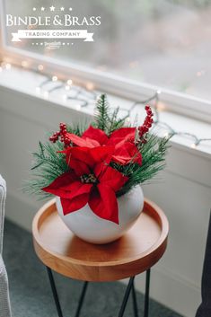 a poinsettia in a white bowl on a small table