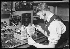 a woman is working on a machine in a room full of other machines and equipment