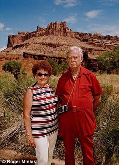 an older man and woman standing next to each other in front of a desert landscape