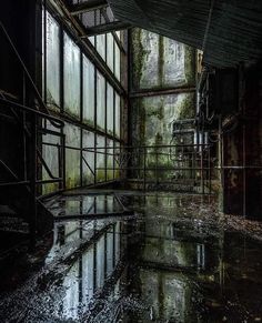 an abandoned building with lots of windows and water