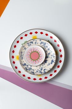 two plates with designs on them are sitting on a colorful striped tablecloth, one is empty