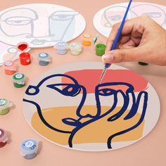 a person is drawing on a plate with paint and pencils next to some buttons