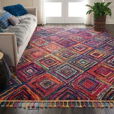 a living room area with a couch and colorful rugs on the floor in front of a window