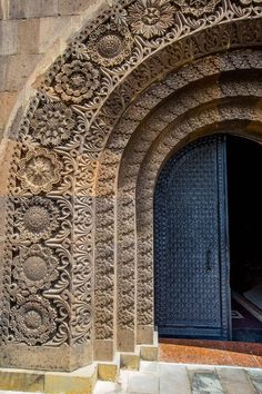 an intricately carved door is shown on the side of a stone building with steps leading up to it