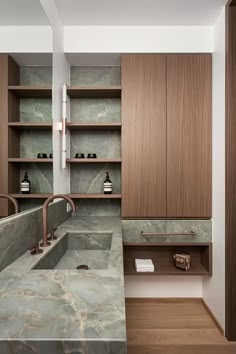 a bathroom with marble counter tops and wooden shelves in the wall, along with two sinks