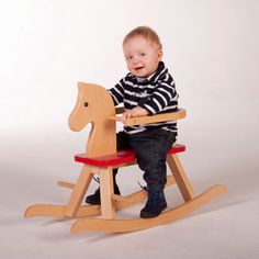 a toddler sitting on a wooden rocking horse