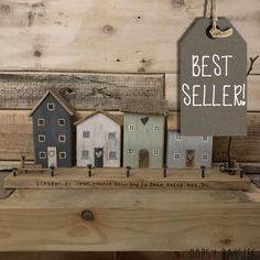 small wooden houses are on display in front of wood planks and a sign that says best seller