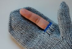 two pictures showing the inside of a gray knitted mitt with a finger on it