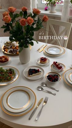 the table is set with plates, silverware and flowers in a vase on it