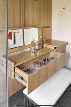 a wooden vanity with drawers and mirror in a small room next to a white bench