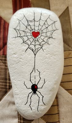 a white stone with a spider web on it and a red heart in the center