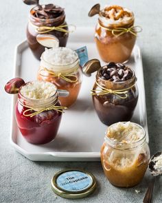 there are many desserts in jars on the tray