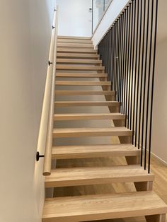 the stairs are made of wood and have black railings on each side, along with white walls