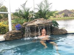 a man swimming in a pool with a waterfall