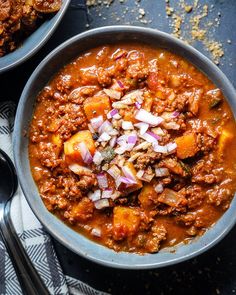 two bowls filled with chili and meat on top of a table