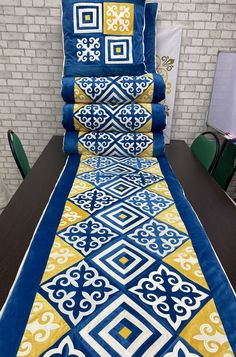 a bed with blue and yellow bedspread on it next to a brick wall